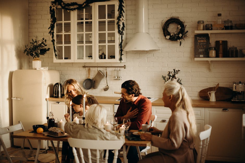Family enjoying a holiday meal in a cozy, warmly lit dining room setting with candles and festive decor.
